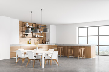 Fototapeta premium white modern kitchen near window. dining area with wooden countertop. Concrete floor. Panoramic windows.