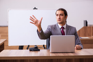 Young male business trainer in the office during pandemic