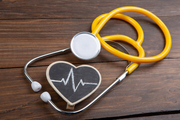 Workplace of a doctor. Stethoscope and little heart on wooden desk background