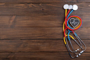 Workplace of a doctor. Colorful Stethoscopes and little heart on wooden desk background -...