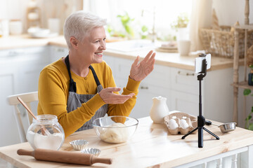 Elderly woman food blogger recording her cooking on smartphone