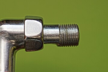 detail from a part of a gray metal plumbing pipe with a thread on a green background