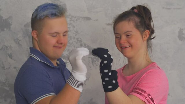 Cheerful teenage couple with Down Syndrome have fun with socks on hands