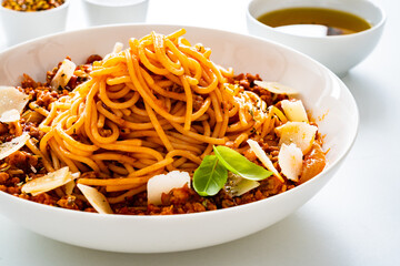 Spaghetti bolognese with minced pork meat and parmesan on white background