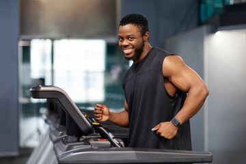Fototapeta na wymiar Joyful black man in sportswear running at gym