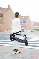 woman with electric scooter crossing the street