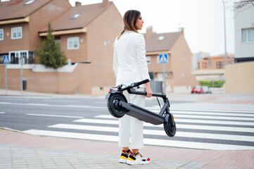 woman with electric scooter crossing the street