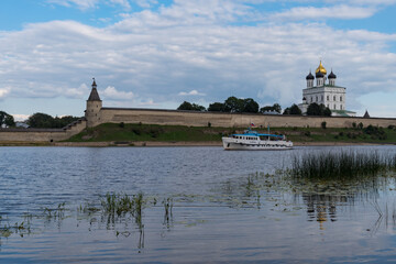 Fototapeta na wymiar Pleasure boat on the river Velikaya opposite Trinity cathedral in Pskov Krom (Kremlin).