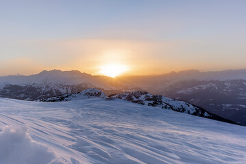 The sunset in winter during a wind storm with the snow being blown away on a peak near Lenzerheide...