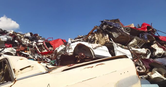 Heap of wrecked cars in big scrapyard on sunny day in recycling facility
