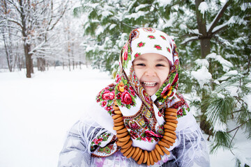Laughing Child wrapped in a scarf in winter at the Pine, with bagels around the neck. The celebration of Shrovetide in Russia
