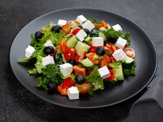 Greek salad on black plate 