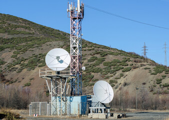 A set of communication antennas and a mast against the background of the mountains.
