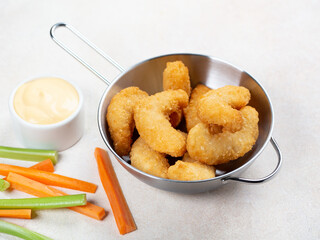 Deep fried shrimps in small pan with cheese sauce and sliced vegetables