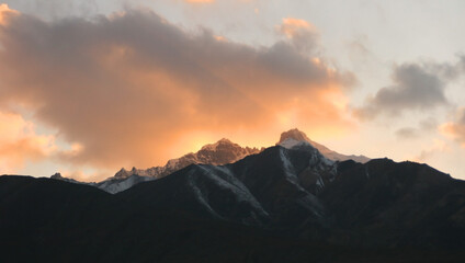 Fototapeta na wymiar A bright orange sunset over sharp black Pamir mountains in the shade