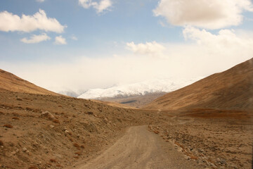 Fototapeta na wymiar Pamir Highway in the desert landscape of the Pamir Mountains in Tajikistan. Afghanistan is on the left