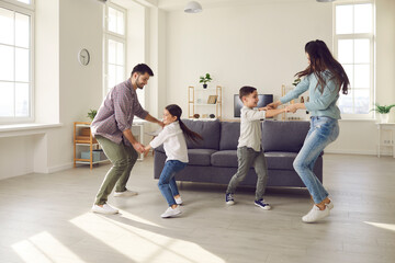 Happy family spending quality time at home. Couple with children playing, dancing and having fun in...
