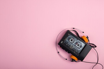 Music listening concept. Vintage cassette tape, audio player and headphones close-up on pink...