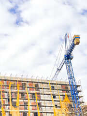 Large crane on a house construction, blue sky background.