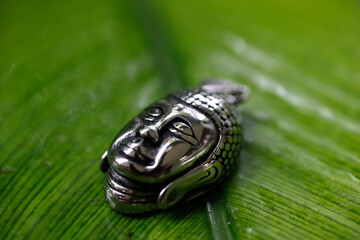 Silver Buddha medallion on a green leave.  Kep. Cambodia.  25.02.2017