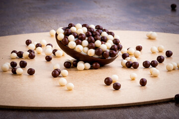 Mini stuffed easter egg with white and black chocolate balls on the top and around on a wooden table.