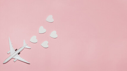Happy Valentine's Day. White passenger plane with hearts on pink background. Flat lay vacation planing and traveling holiday. Holiday travel concept. Top view