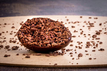 Stuffed chocolate easter egg with grated chocolate on the top and around on a wood table.