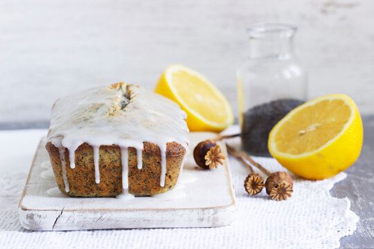 Lemon cake with poppy seeds, covered with glaze on a light background.