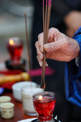 Ceremony in a buddhist chinese temple. Man praying with burning incense sticks. Hue.  Vietnam.  25.02.2017