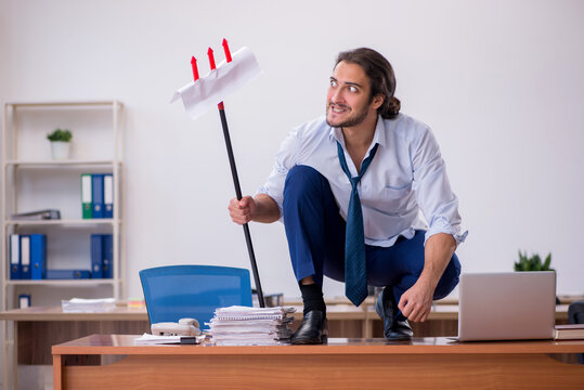 Young devil businessman holding trident in the office