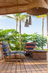 Rolgordijnen Lounge zone in tropical hotel. Outdoor patio with chairs, pillows, table and palms. Paradise in Zanzibar. Vacation in Africa. Exotic leisure. Luxury lifestyle. Sunny day in paradise. © Nataliia