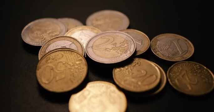 Shallow depth of field (selective focus) and macro image with a 2 Euro metal coin near other Euro coins on black background.
