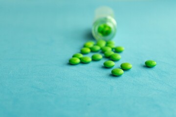 Bottle and scattered pills on color background, top view. Space for text