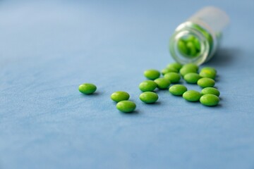 Bottle and scattered pills on color background, top view. Space for text