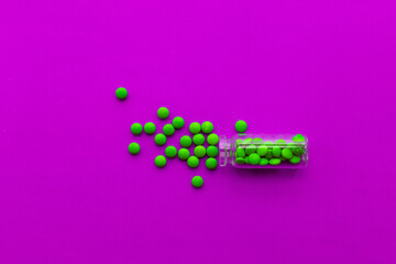 Bottle and scattered pills on color background, top view. Space for text