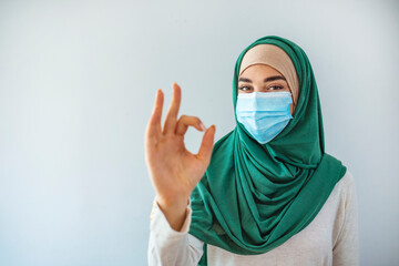 Pretty and confident muslim young woman wearing medical protective face mask to protect infection from Coronavirus in studio on isolated white background portrait. Covid19 concept