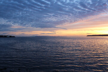 Sunset light reflects sky, beneath the clouds, and surface of the sea