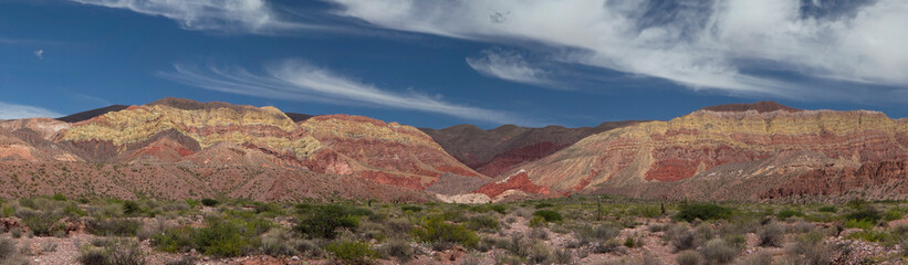 Desert background. Panorama view of the arid desert and colorful mountains under a blue sky.	