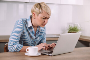 Focused serious woman working on laptop at home Female using portable computer