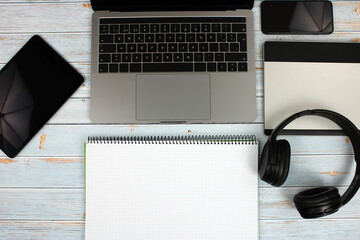 Top view of a computer accompanied by a tablet, a mobile phone and office supplies on vintage wooden background