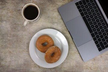 Top view of a computer accompanied by a tablet, a mobile phone and coffee with scones on an abstract background