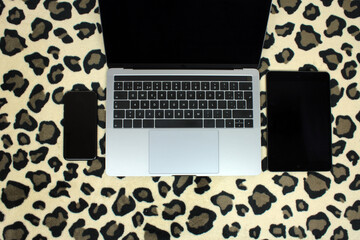 Top view of a computer accompanied by a mask and hydroalcoholic gel on a jaguar skin background © JoseFelix