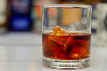 Old fashioned glass with scotch whisky and ice cubes on the bar