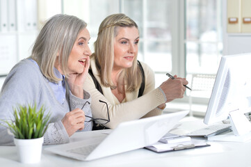 two excited mature women working in office
