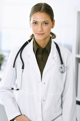 Woman-doctor standing and looking at camera. Perfect medical service in clinic. Medicine and healthcare