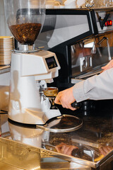 Close-up of a masked barista preparing a delicious coffee at the bar in a cafe. The work of restaurants and cafes during the pandemic.