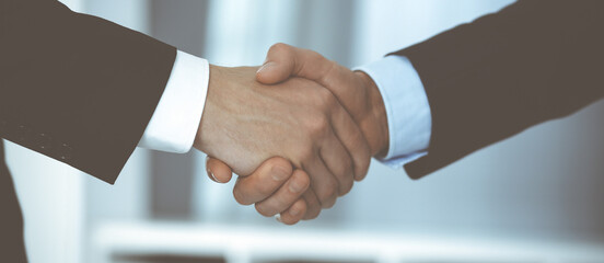 Obraz premium Business people shaking hands after contract signing while standing in a modern office. Teamwork and handshake concept