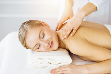 Obraz na płótnie Canvas Beautiful caucasian woman enjoying back massage with closed eyes in sunny Spa salon