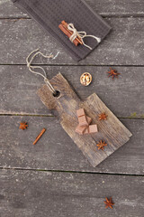 Pieces of chocolate, cinnamon sticks and star anise on a wooden board. High quality photo