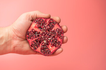 a hand squeezing juice from a pomegranate into a glass